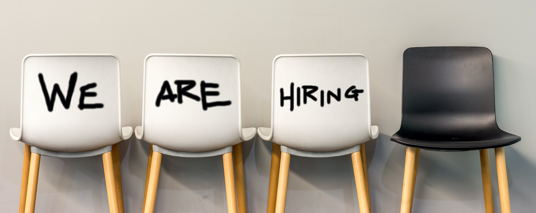 Empty chairs lined up against a wall saying 'We are hiring'